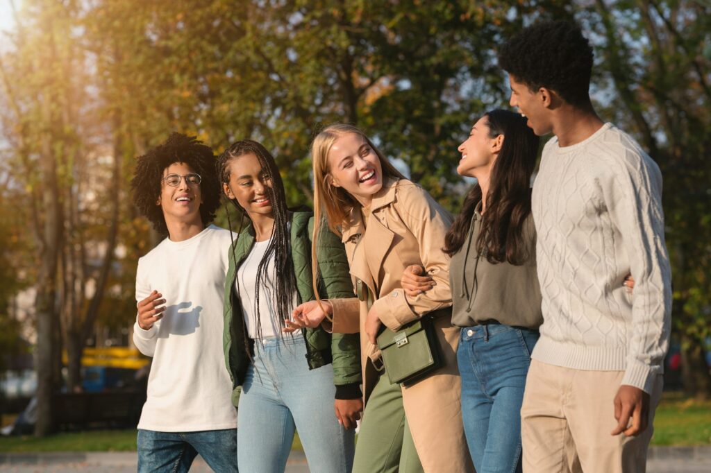 International group of teenagers laughing while walking by park